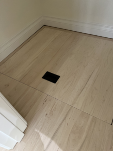 A newly installed hardwood floor featuring a discreet access panel by Birdseye Hardwoods LLC in Portland, OR