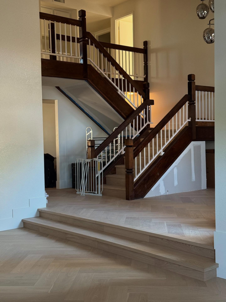 Beautiful finished herringbone hardwood floor and grand staircase completed by Arizona Prestige Flooring in Surprise, AZ