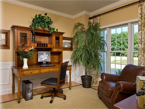 A beautifully finished home office interior with a wooden desk and large window by Charlew Builders in Schenectady, NY.