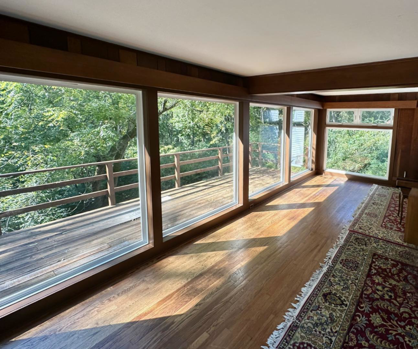 A beautifully finished interior room with large windows and a wooden deck view by Imagine It Home Improvements Co. in Bethlehem, PA.