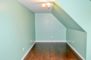 A newly finished interior room with light green walls and dark wood flooring by Patriot Construction in Rochester, NY.