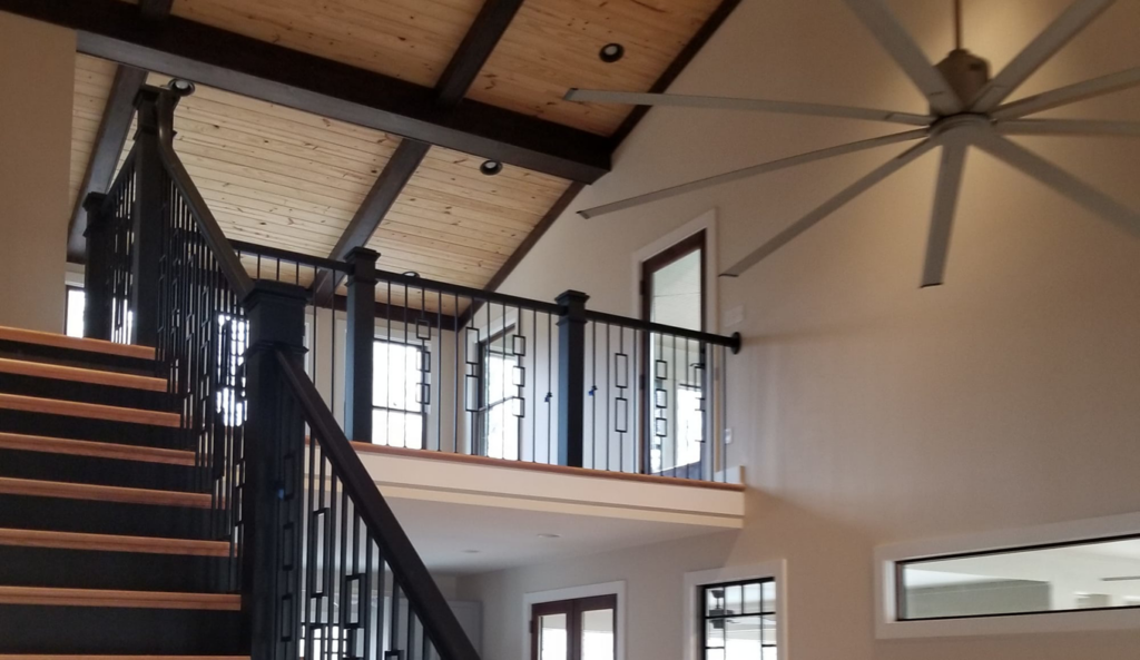 A beautifully finished interior with a modern staircase, vaulted ceiling, and large fan by PrimeTime Painting in Bowling Green, KY.