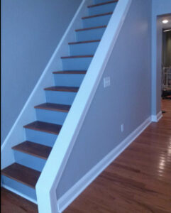 A finished interior staircase with blue walls, white trim, and wooden treads by S-G General Contracting LLC in Philadelphia, PA.