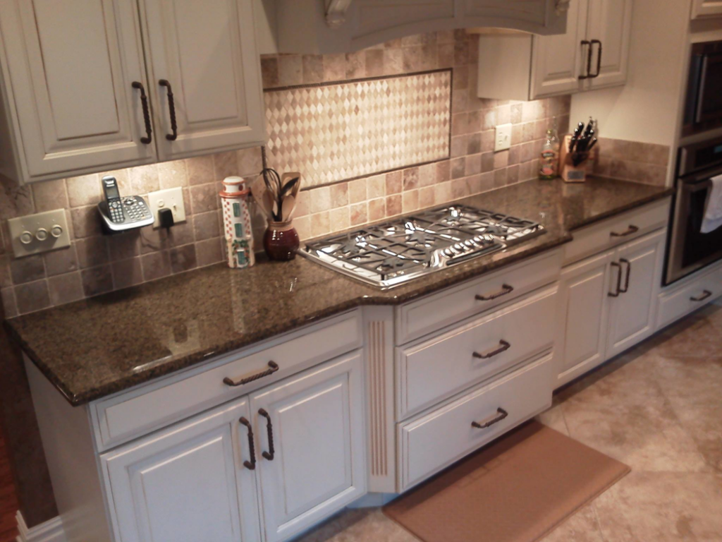 A beautifully finished kitchen featuring dark granite countertops and a tiled backsplash by Alfortish Marble & Granite, LLC in Baton Rouge, LA.
