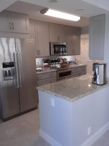 A finished kitchen with gray cabinets and granite countertops by Corley Construction Inc in Fort Lauderdale, FL