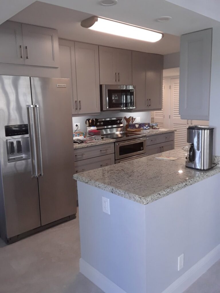 A finished kitchen with gray cabinets and granite countertops by Corley Construction Inc in Fort Lauderdale, FL