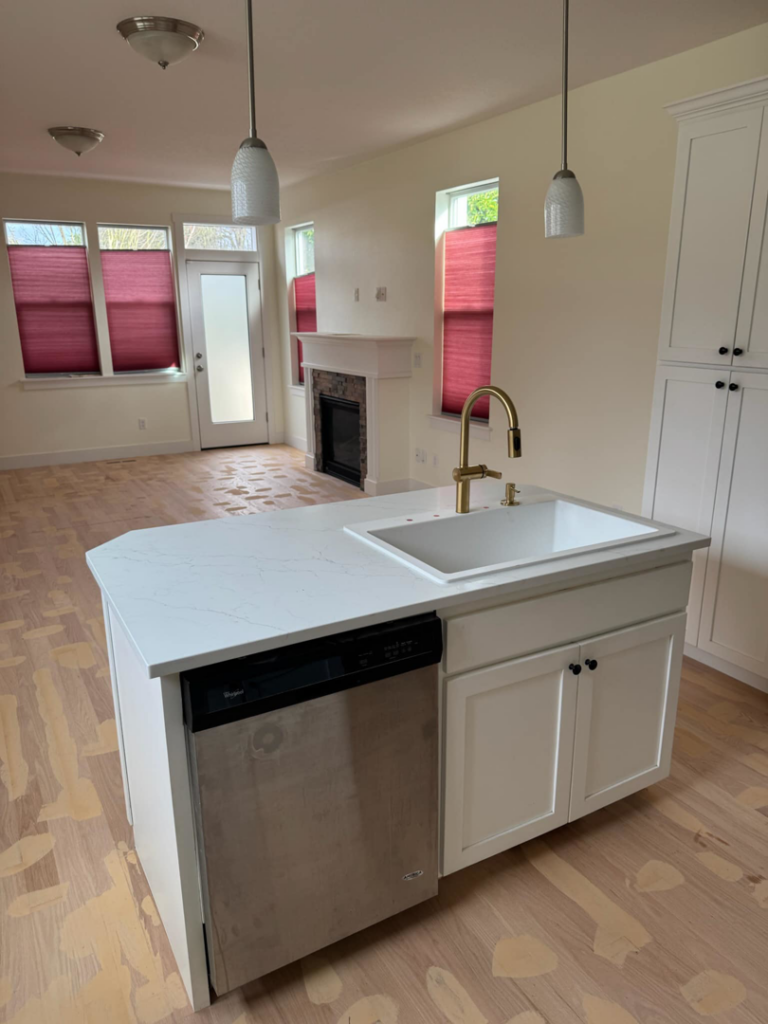 A finished white kitchen with a new island, sink, and dishwasher installed by Restore Renew Remodel in Portland, OR.