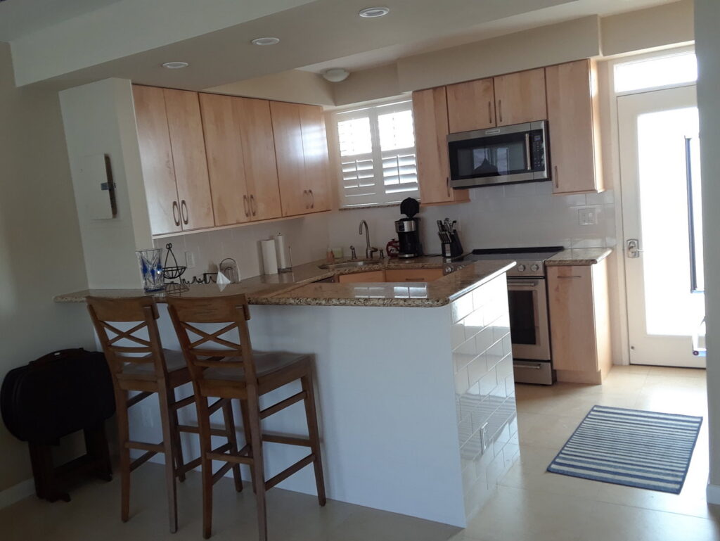 A finished kitchen with light wood cabinets and granite countertops by Corley Construction Inc in Fort Lauderdale, FL