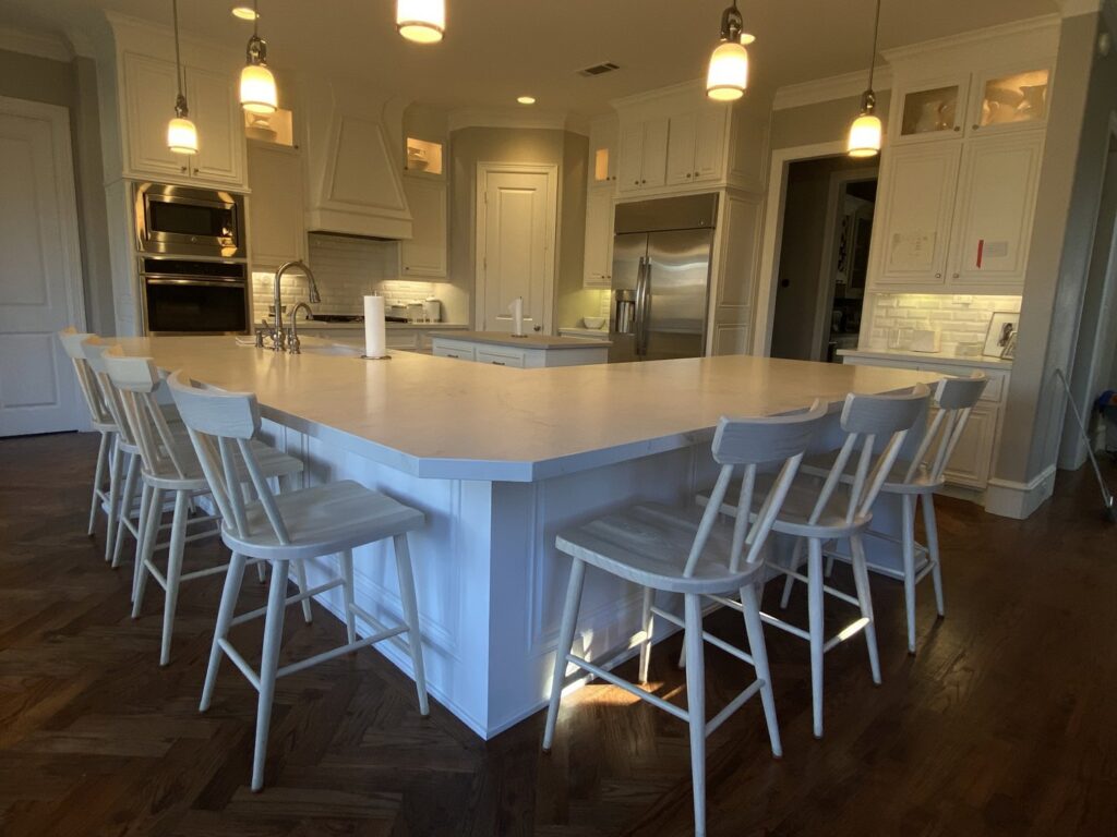 A spacious, finished kitchen remodel featuring white cabinets, a large island, and pendant lighting by Elite Handyman & Remodeling in Dallas, TX.