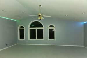 A finished living room with painted walls, recessed lighting, and a ceiling fan by FG Drywall, Finishing and Painting in Champaign, IL.
