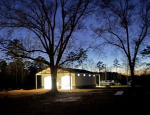 A finished metal barn or building illuminated from within at dusk, built by Southern Style Barns & Buildings LLC in Lake Charles, LA.
