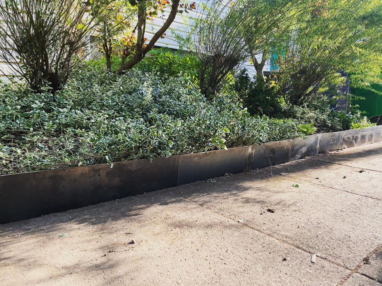A finished metal planter box installed along a sidewalk by Loper & Slag metal fabrication design in Portland, OR.