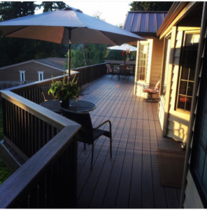 A spacious finished outdoor deck with patio furniture and umbrellas, built by Kalau Builders LLC in Eugene, OR.