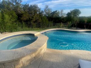 A finished swimming pool and hot tub area with clear water by 5 Daughters Total Outdoors in Austin, TX.