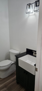 A newly finished powder room with a modern vanity and farmhouse sink by Susquehanna Valley Builders in Harrisburg, PA.