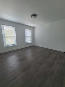 A finished room showcasing dark laminate flooring and white walls, a project by Modern Image Construction LLC in El Paso, TX.