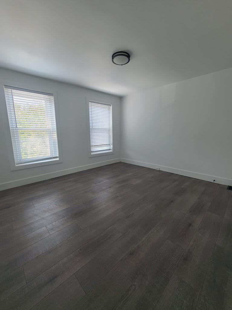 A finished room showcasing dark laminate flooring and white walls, a project by Modern Image Construction LLC in El Paso, TX.