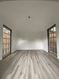 A newly remodeled room with fresh paint and modern laminate flooring installed by Elite Handyman & Remodeling in Dallas, TX.