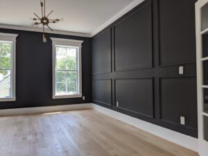 A newly finished room featuring dark decorative wall paneling and light hardwood flooring by BizMick Construction in Coventry, RI.