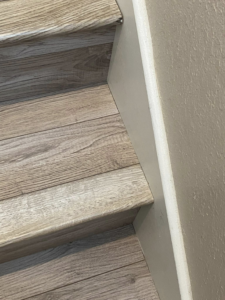 Close-up of newly installed wood-look flooring on a staircase, completed by DeLeon Contracting LLC in San Antonio, TX.