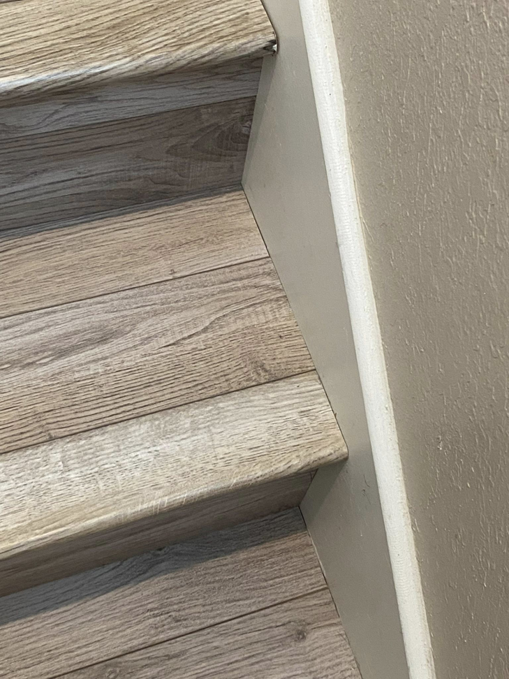 Close-up of newly installed wood-look flooring on a staircase, completed by DeLeon Contracting LLC in San Antonio, TX.
