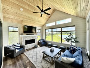 A beautifully finished sunroom with a vaulted wooden ceiling, ceiling fan, and stone fireplace by Kahle Builders, LLC in Waukesha, WI.