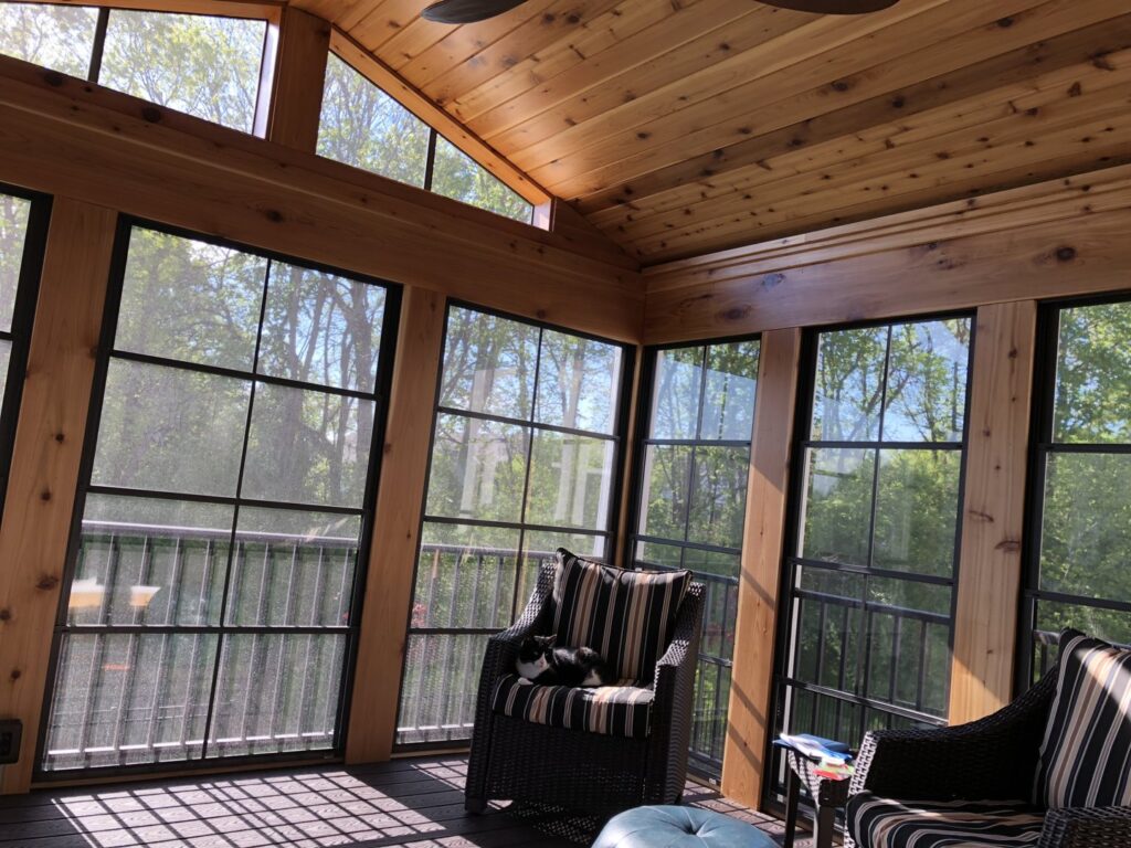 Finished sunroom interior with a wooden ceiling, large windows, and comfortable furniture by Tschida Construction in Cologne, MN.