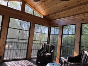 Finished sunroom interior with a wooden ceiling, large windows, and comfortable furniture by Tschida Construction in Cologne, MN.