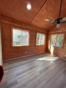 The interior of a finished sunroom with wooden walls, ceiling, and new flooring by A.G Deck & Painting in Charlotte, NC.
