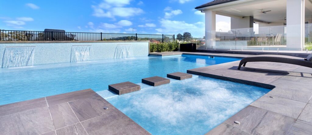 A wide shot of a finished swimming pool and hot tub area by 5 Daughters Total Outdoors in Austin, TX.