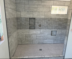 A beautifully finished tiled shower with grey and hexagonal patterns by Burrell Tile INC in Cottage Grove, OR.