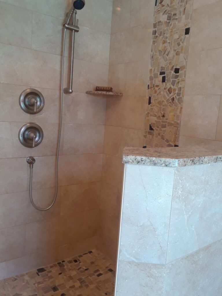 A finished tiled shower with a decorative mosaic column by Corley Construction Inc in Fort Lauderdale, FL