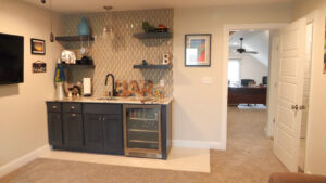 A newly finished wet bar installation with cabinets, sink, and tiled backsplash by Rave Homes - Missouri in Columbia, MO.