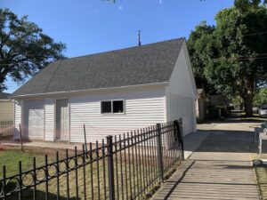 A finished white garage exterior with a dark roof and two doors by A-Windy City Garages & Doors in Chicago, IL.