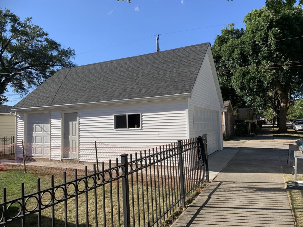 A finished white garage exterior with a dark roof and two doors by A-Windy City Garages & Doors in Chicago, IL.