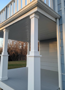 A beautifully finished white porch ceiling with sturdy columns by Dry Deck Ceilings KC in Kansas City, KS.