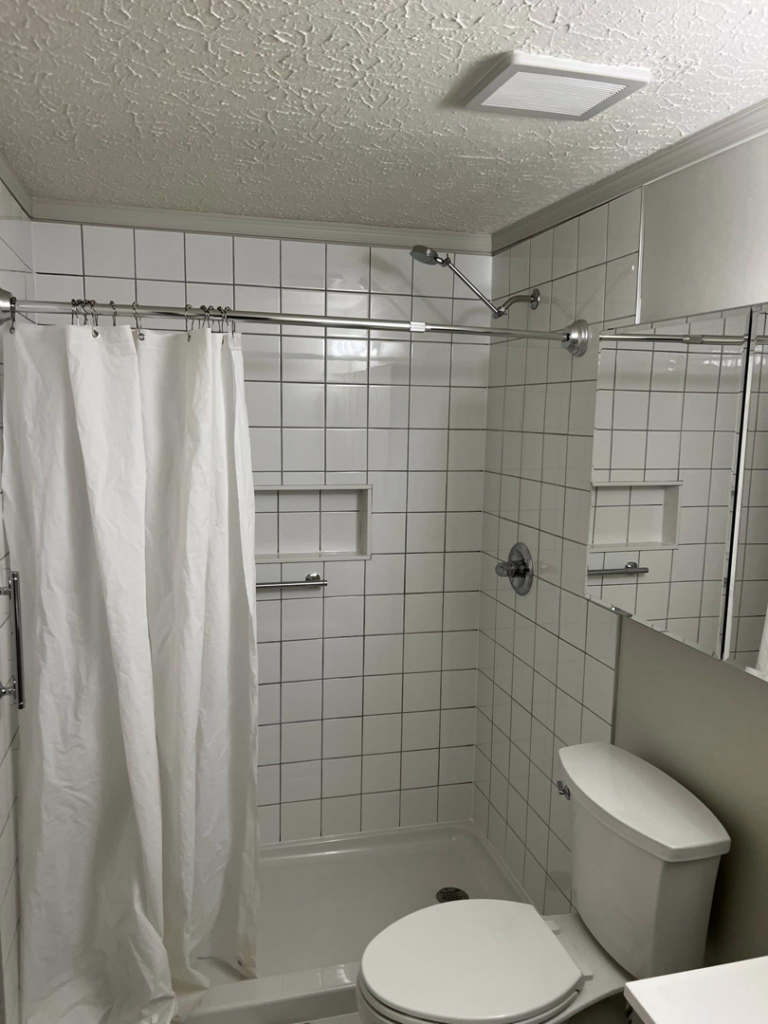 A finished white tiled shower with a curtain and toilet installed by Home Changes in Knoxville, TN