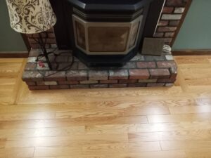 A newly finished wood floor expertly installed around a brick fireplace hearth by Robert C. Mihaich Wood Flooring in Worcester, MA.