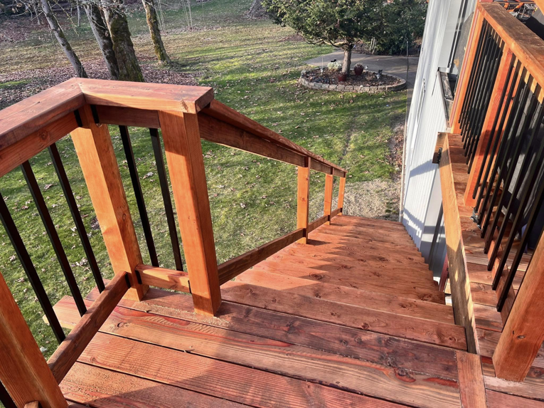 A close-up of a finished wooden deck railing and stairs by One Up construction llc in Springfield, OR.