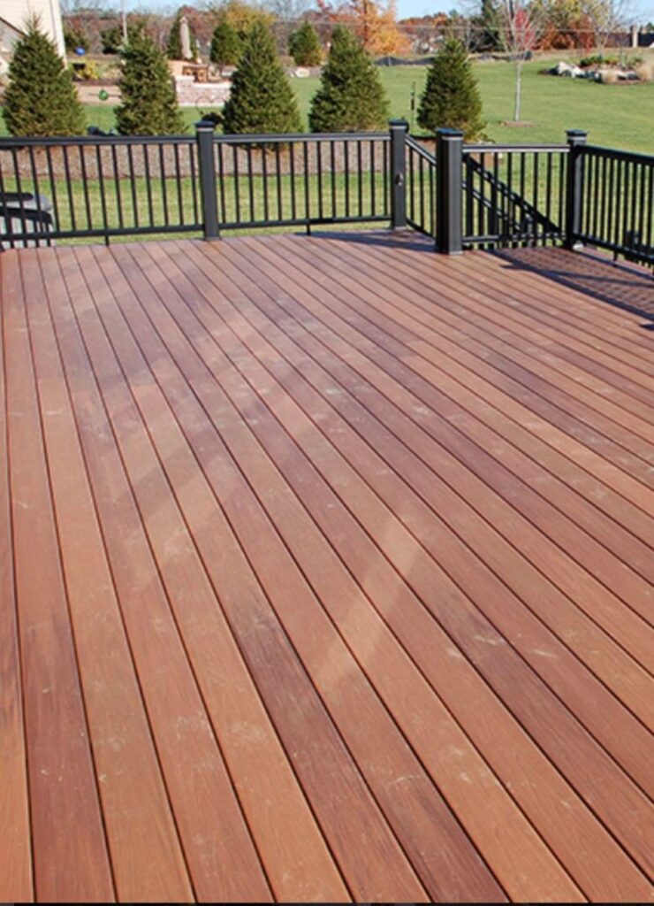 A beautifully finished wooden deck with black railings, showcasing outdoor living space improvement by Vazquez Quality Construction Inc in Aurora, CO.