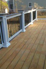 A finished wooden deck featuring decorative white and black railings by Fence Me In And Decks Too in Glen Allen, VA.