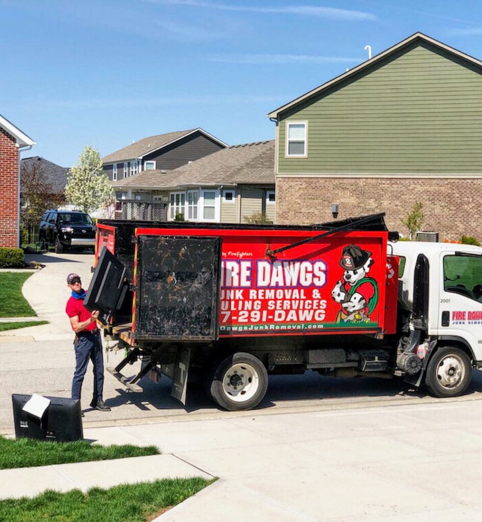 A Fire Dawgs Junk Removal employee loads a large item into the back of a junk removal truck in Bloomington, IN.