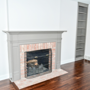 A renovated fireplace with a grey mantel and built-in shelves by Patriot Construction in Rochester, NY.