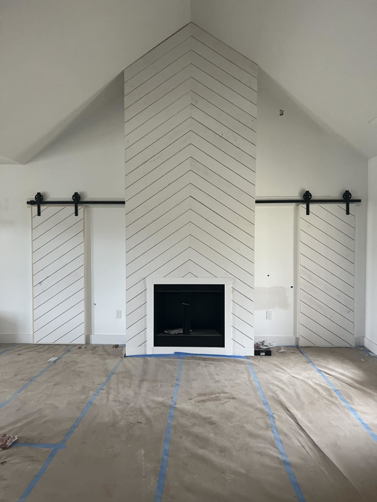A newly installed fireplace with a chevron pattern surround and barn doors by Cord Construction in Winchester, KY