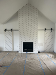 A newly installed fireplace with a chevron pattern surround and barn doors by Cord Construction in Winchester, KY