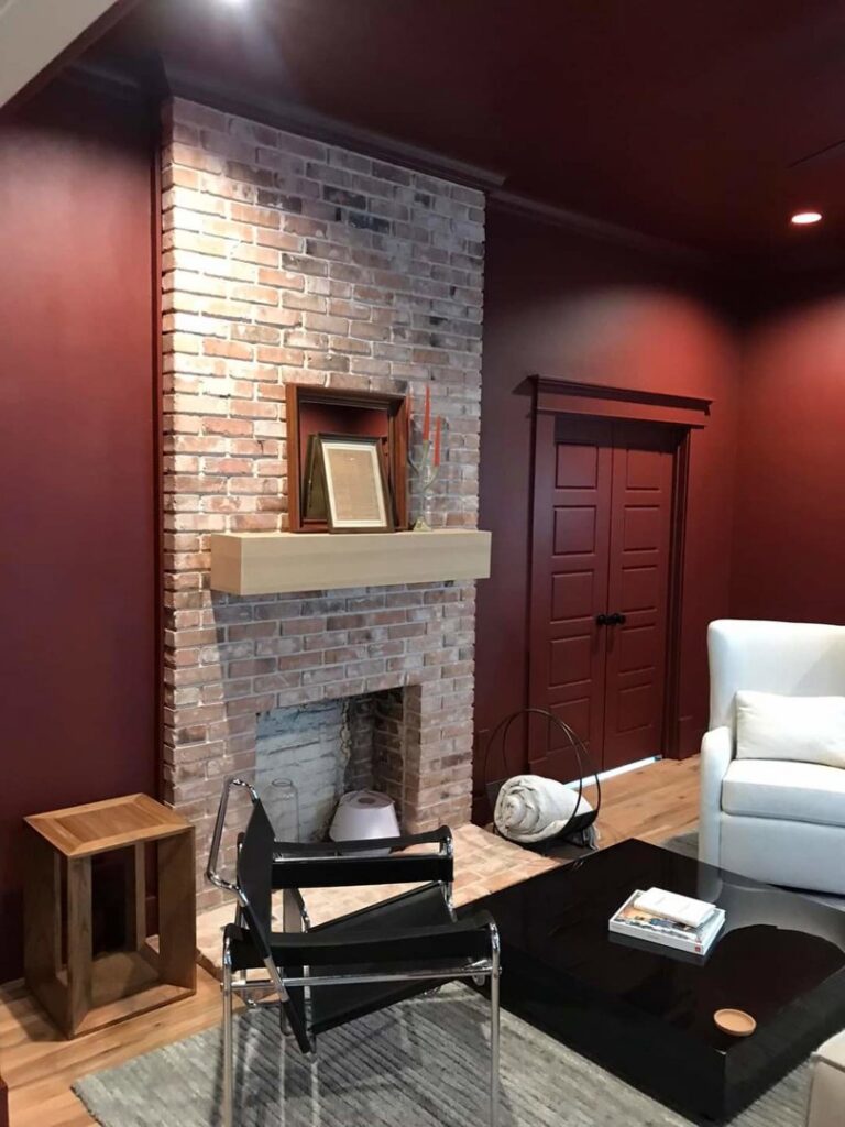 A remodeled living room featuring a new brick fireplace and wooden mantel by Finesse Painting and Remodeling in Fort Worth, TX.