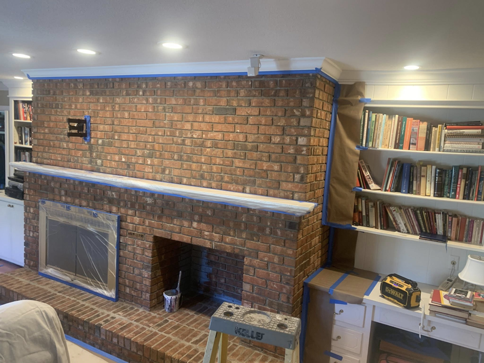 A brick fireplace and built-in shelves taped off and prepped for painting by Carolina Handyman Builder in Taylors, SC.