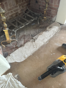 Fireplace hearth with a vacuum cleaner, showing cleanup after handyman work by Paint Co in Canyon Lake, CA