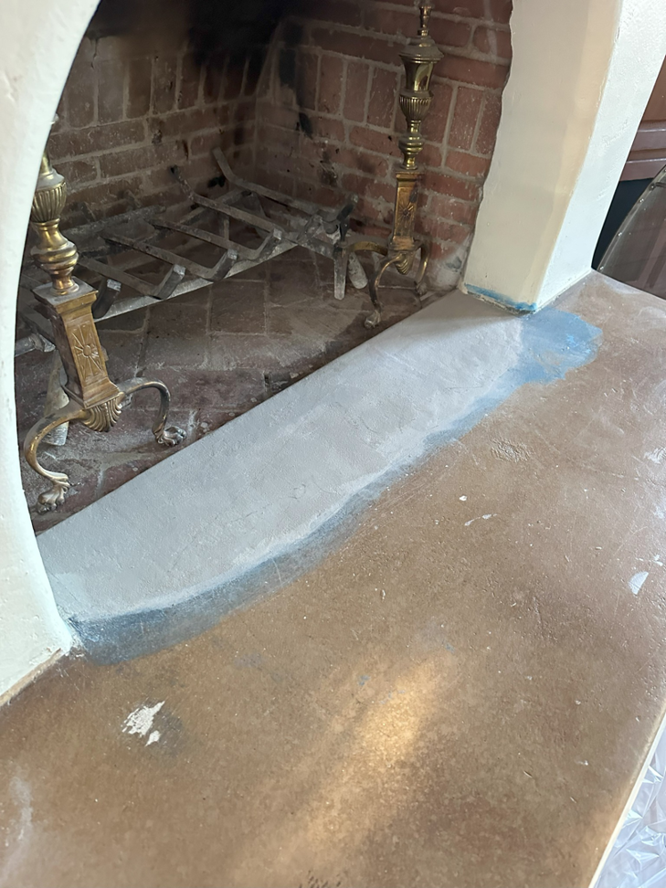 A fireplace hearth with a new patch of material, showing repair work by Paint Co in Canyon Lake, CA
