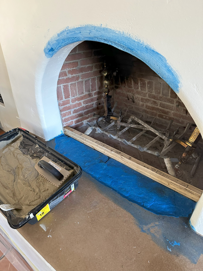 Fireplace hearth with blue tape and material, showing repair preparation by Paint Co in Canyon Lake, CA